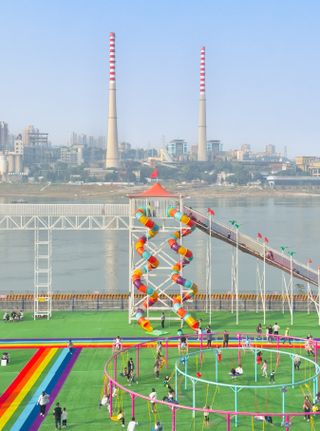 Children's playground in the foreground, river and two industrial chimneys in the background