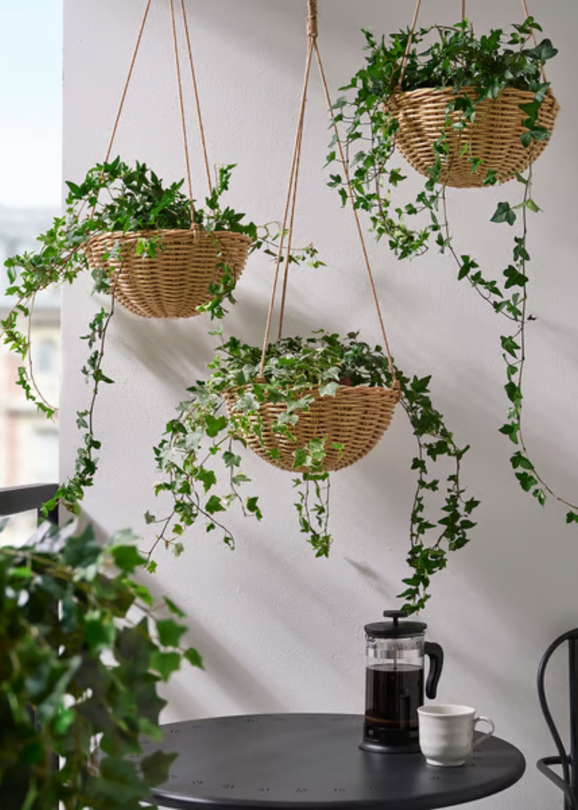 Rattan hanging and potted plants on a balcony with a small dining table