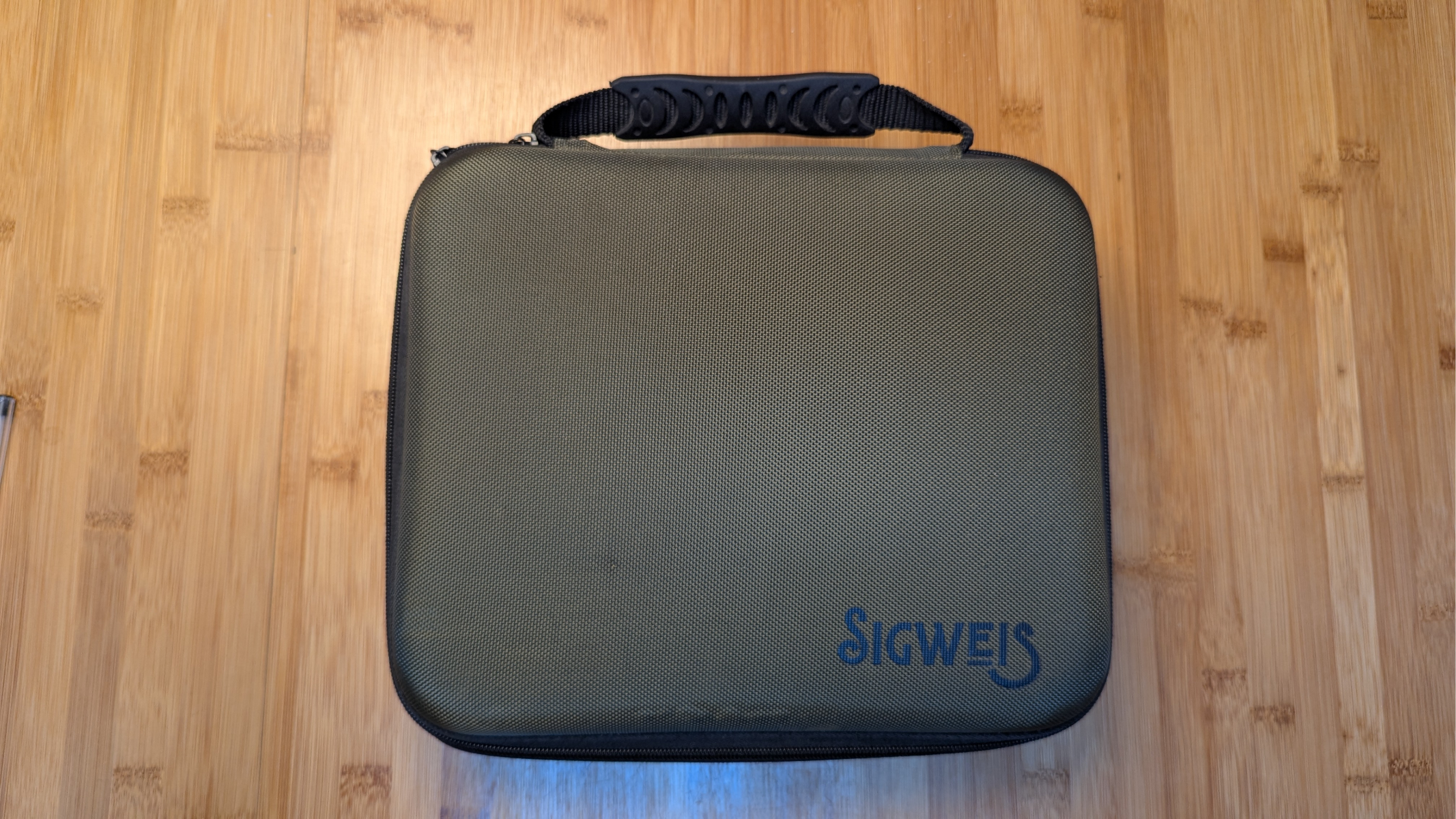 علبة مجهر للرؤية الليلية من Sigweis على طاولة خشبية.