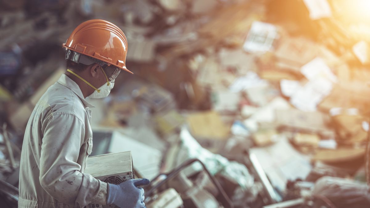 A landfill worker navigating a vast ocean of electronic waste at a landfill site