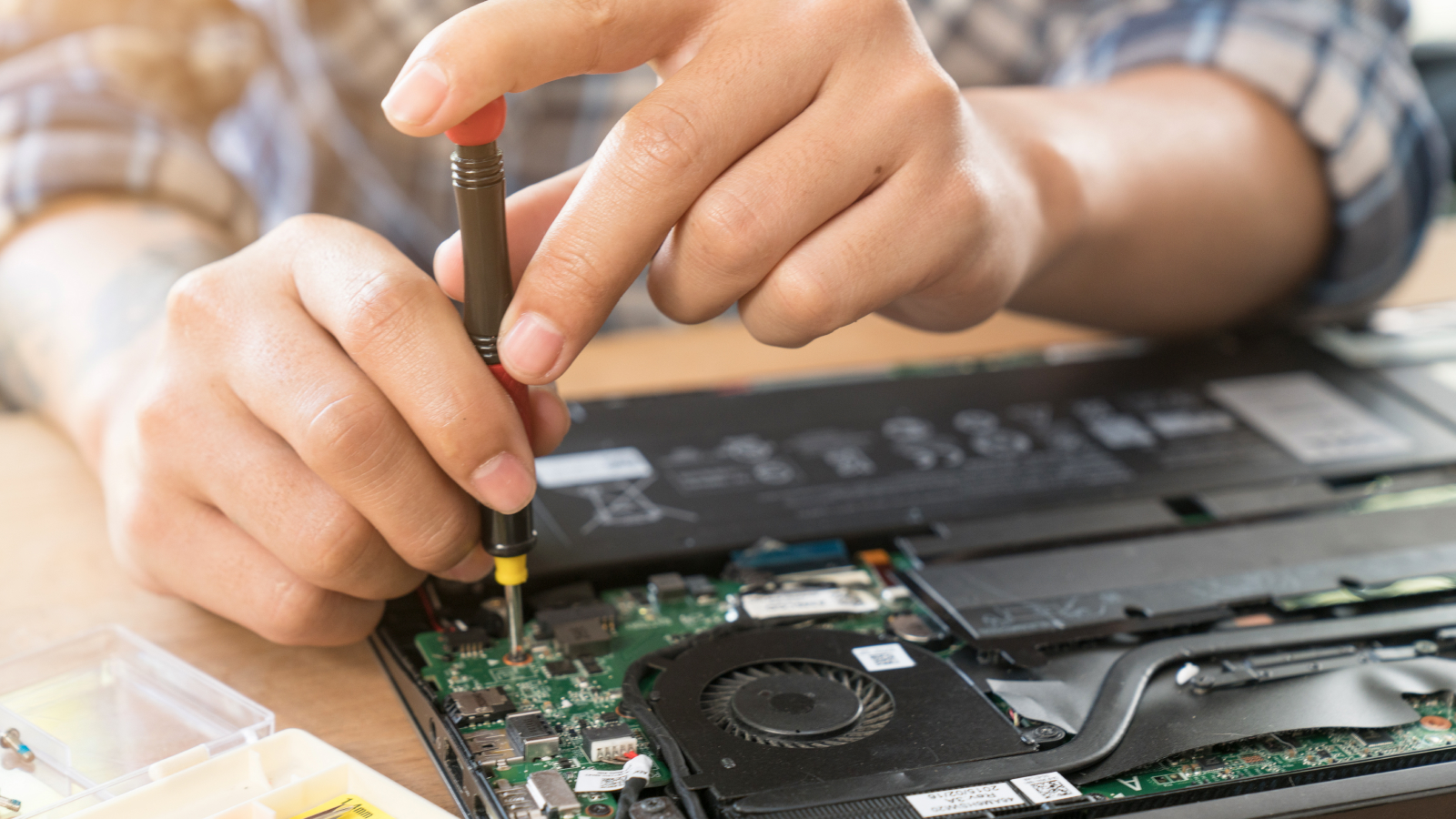 Person using a screwdriver to repair a laptop.