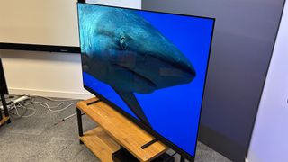 Philips OLED909 OLED TV slight angle on wooden hi-fi bench with shark on screen