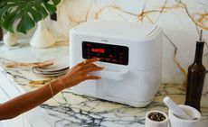 The ‘Zone 9QR’ trizone air fryer. A white square air fryer with a digital display on a white marble kitchen surface.