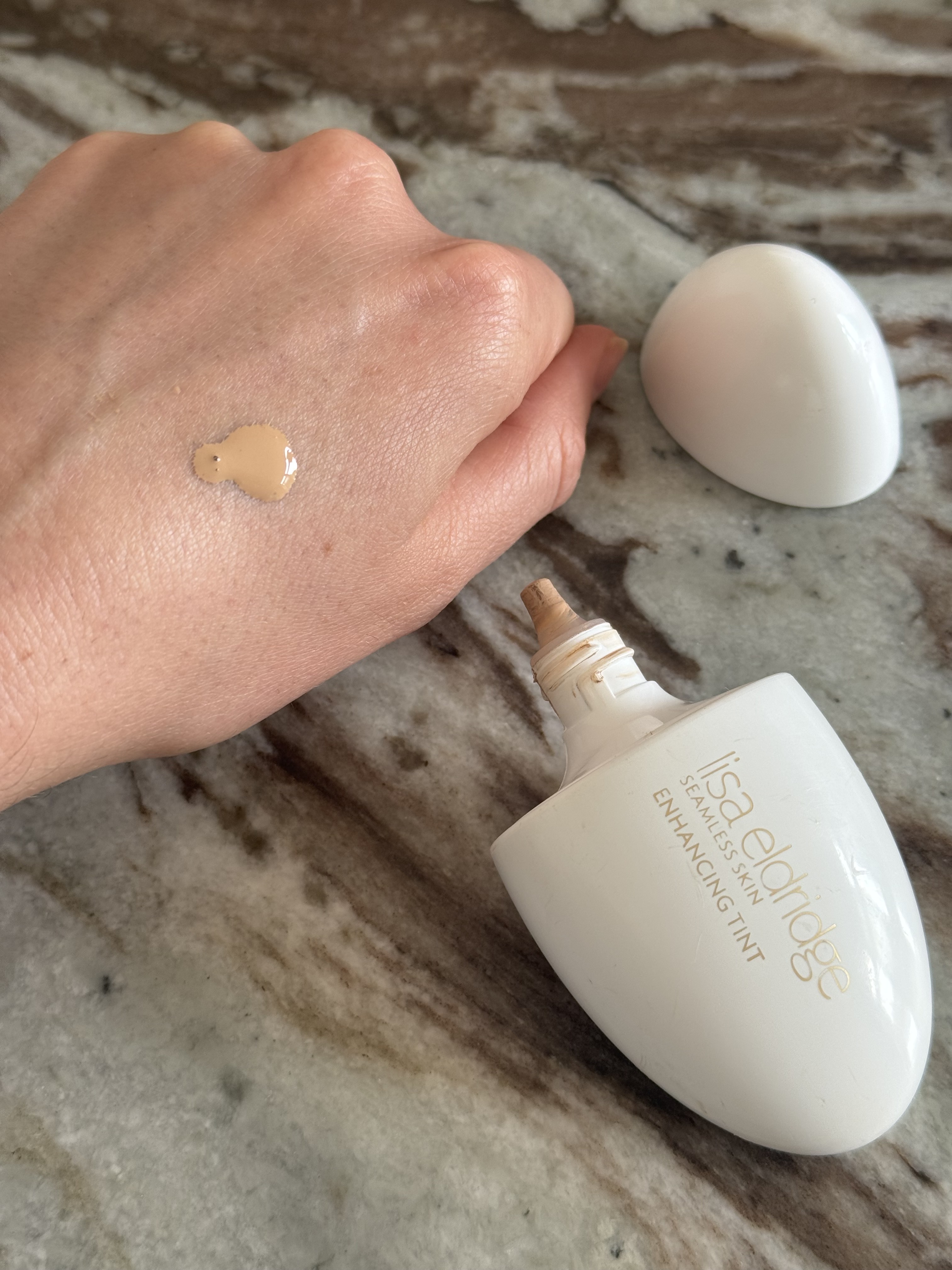 The Lisa Eldridge Seamless Skin Enhancing Tint in shade T7 on the back on Eleanor's hand