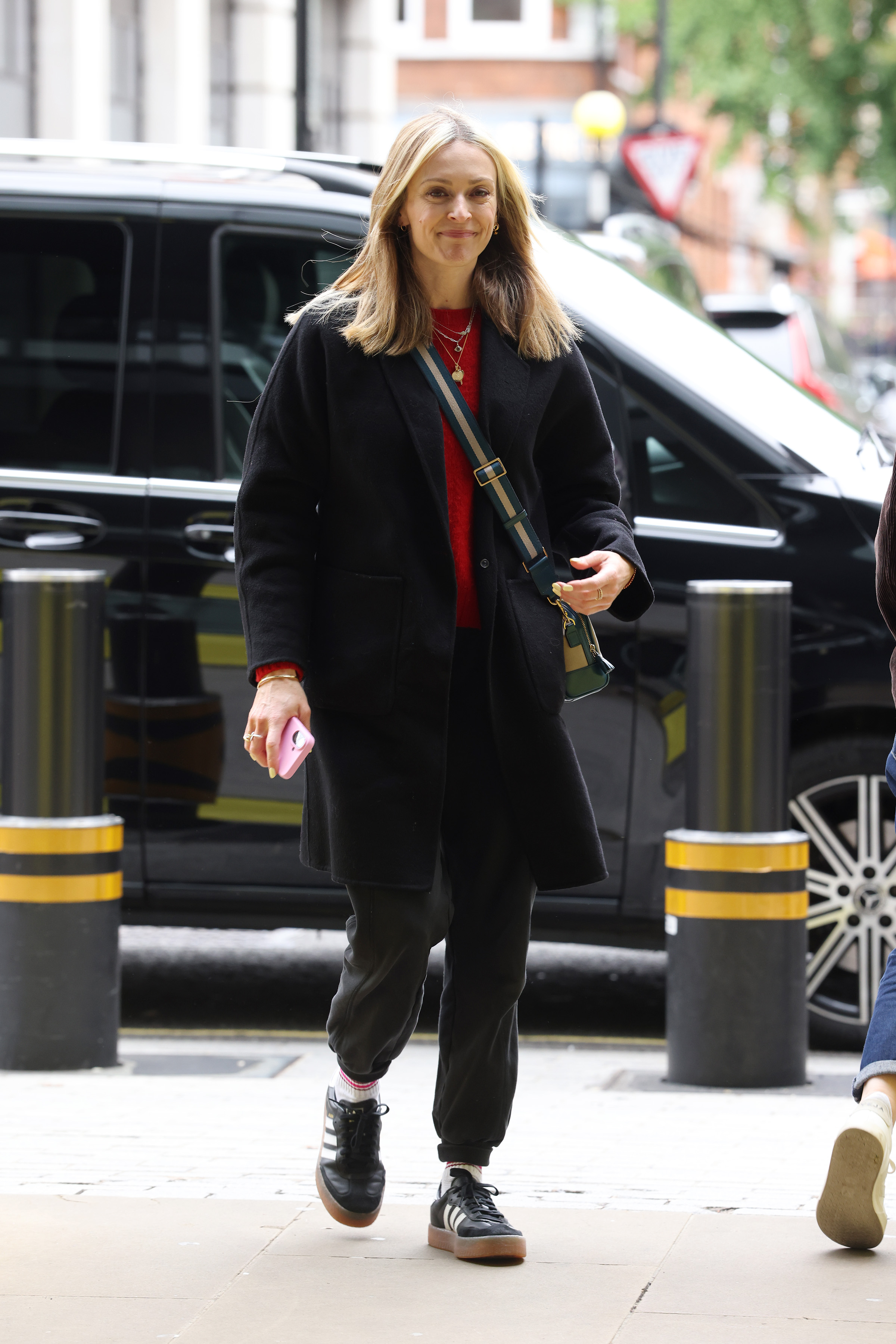 Fearne Cotton wearing joggers, red knit jumper, black tailored coat and platform adidas samba trainers in London on 12 June, 2026