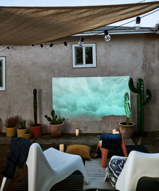 White outdoor seating facing projector screen in yard