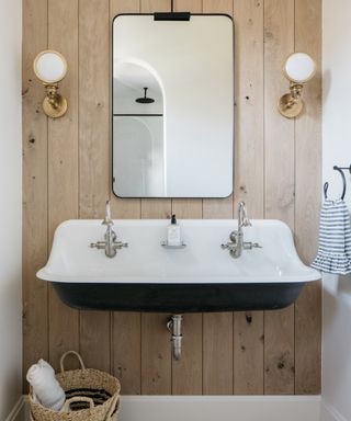 Driftwood style bathroom with wide basin, black mirror, wall ights, basket, coastal feel