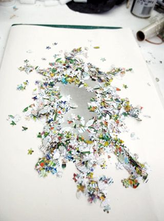 Hundreds of pieces of the floral art piece displayed on a table.