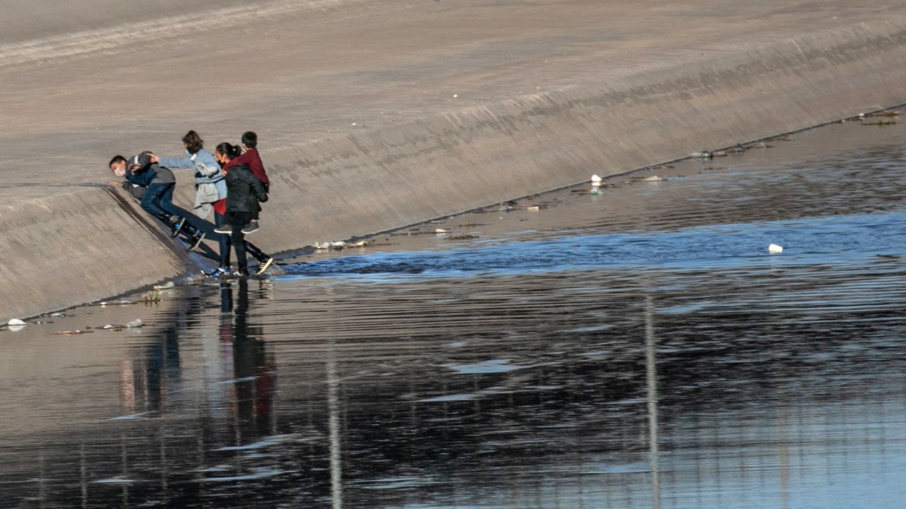 Migrants cross the shallow Rio Grande to gain entry into El Paso, Texas