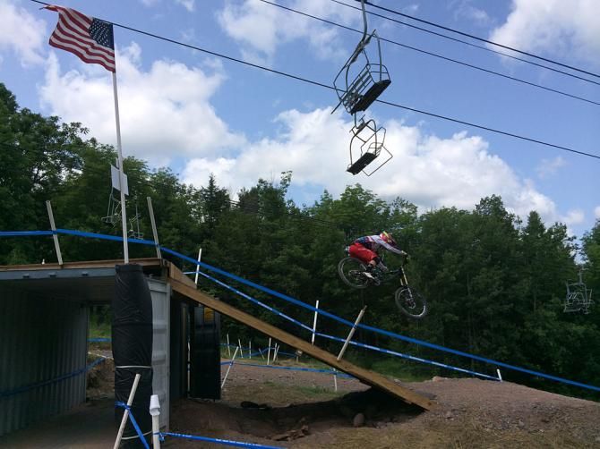 A junior downhiller catches air at a point where the downhill course crosses the cross country course
