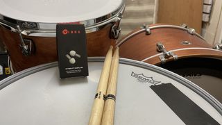 Vibes Hi Fidelity Earplugs on top of a snare drum next to a pair of drumsticks