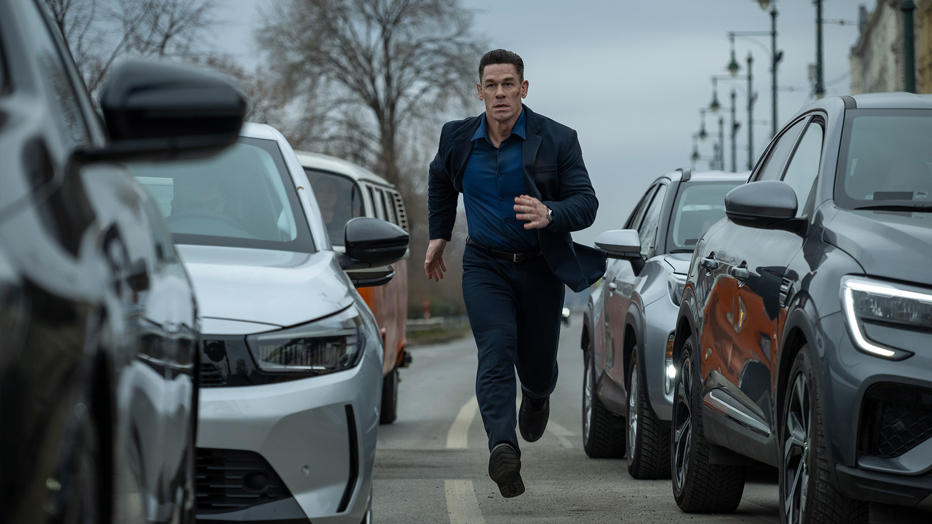 John Cena runs in between cars in Apple TV's Matchbox The Movie