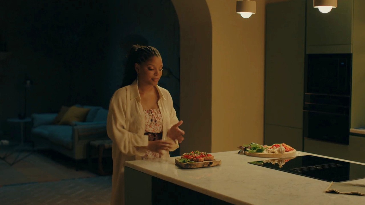 Halle Bailey standing in front of bruschetta in You, Me, and Tuscany.