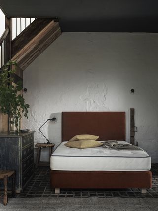 A bedroom with vaulted ceiling and exposed beams with a bare mattress on the bed