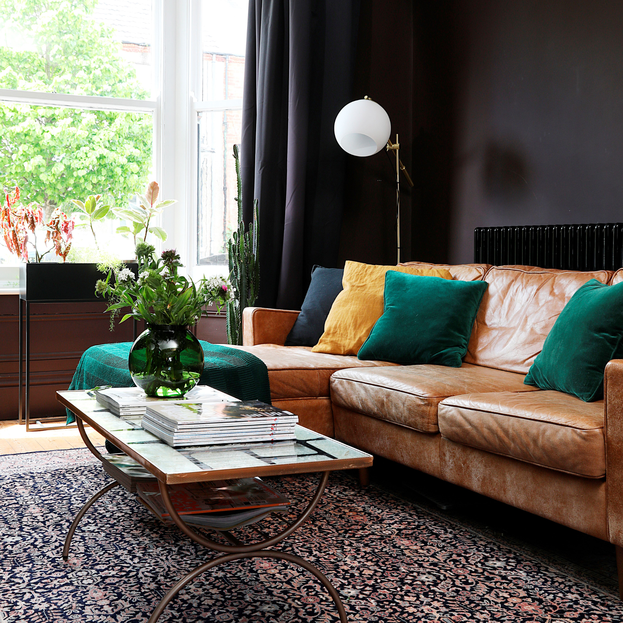 Dark painted living room with leather L-shaped sofa, patterned rug and decorated coffee table