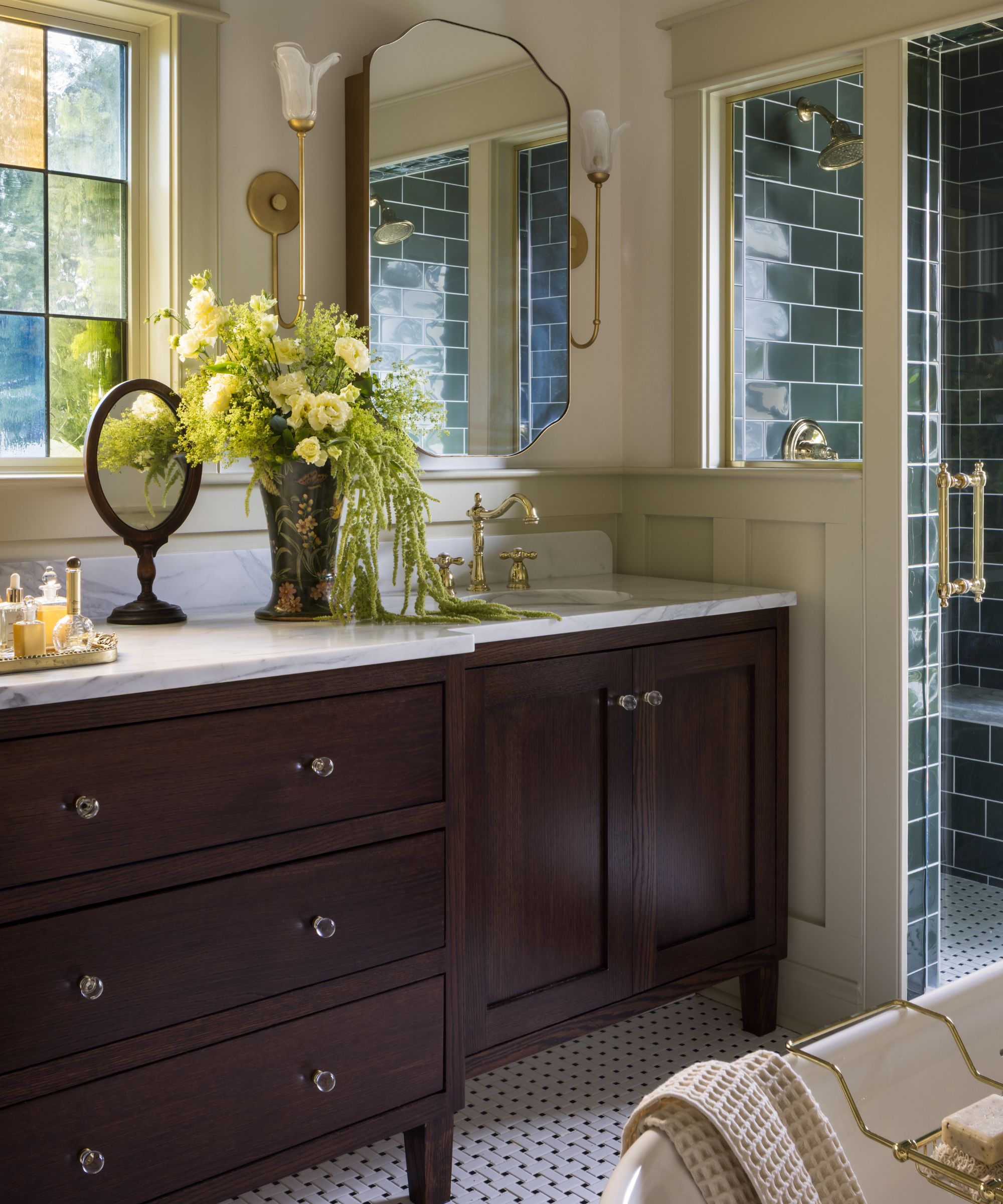 a traditional primary bathroom with dark wooden vanity, stained glass window, panelling, and green gloss shower tiles