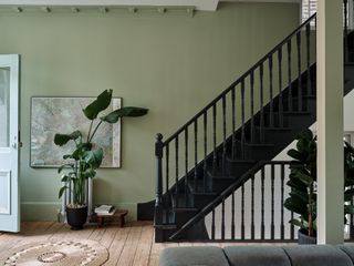 A green entryway with black staircase