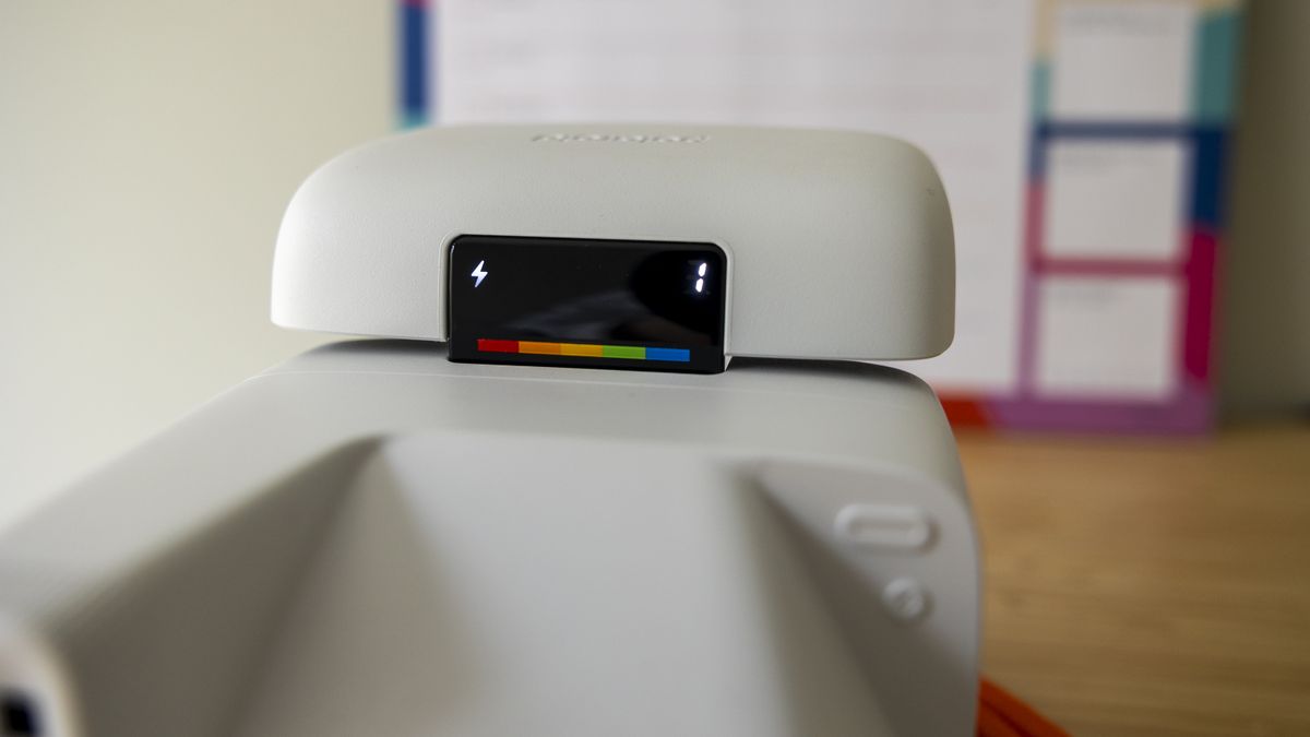 A white Polaroid Flip camera sits on a wooden desk