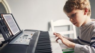 Young child playing a beginner keyboard 