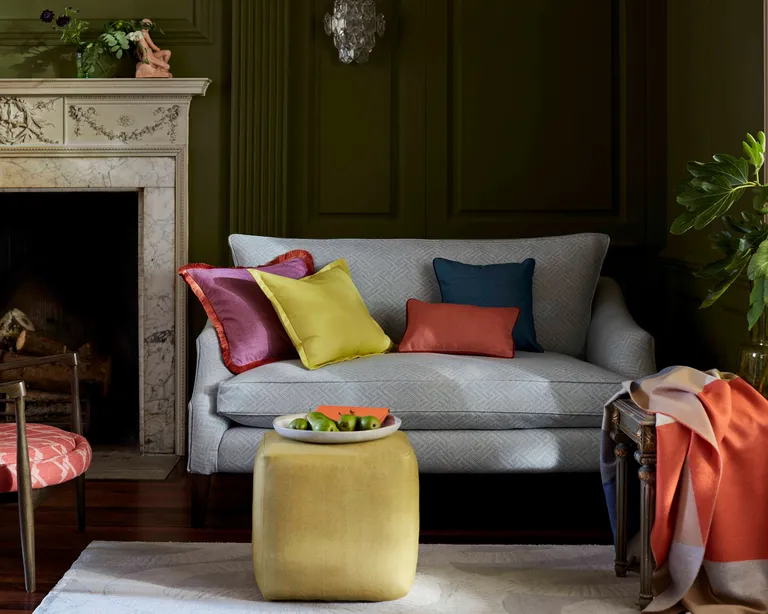 A dark green living room with grey sofa and bright colored cushions