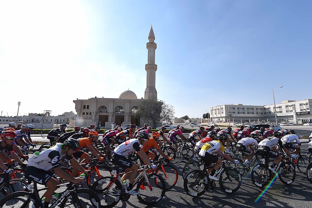Riders pass a mosque during stage 5 at the Tour of Qatar