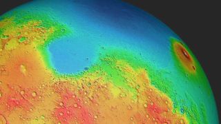 a topographical map of mars from a position seen in space. a huge basin in blue is at the top with higher altitude regions surrounding it, in green, red and orange.