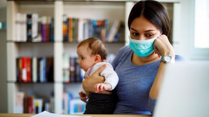 Unemployed woman wearing face mask holding her baby