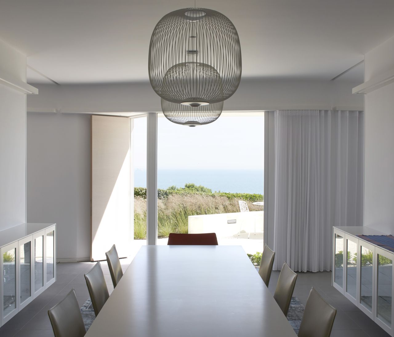 white dining room with pendant light and view of sea