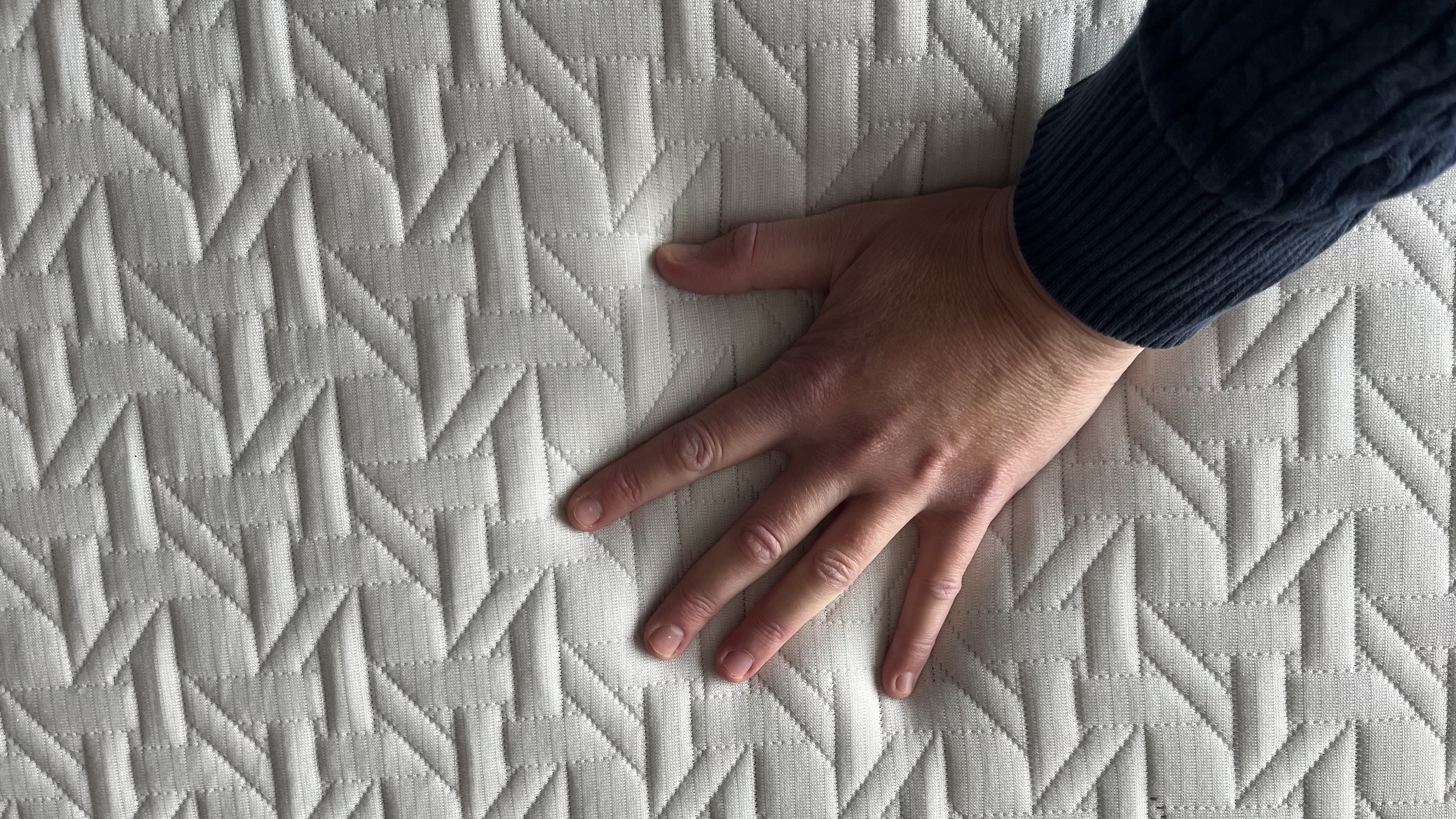 reviewers hand on the nectar classic hybrid mattress cover to show responsiveness and detail of cover