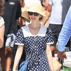 Lily Collins wears beige mesh ballet flats with a polka dot dress and a straw hat.