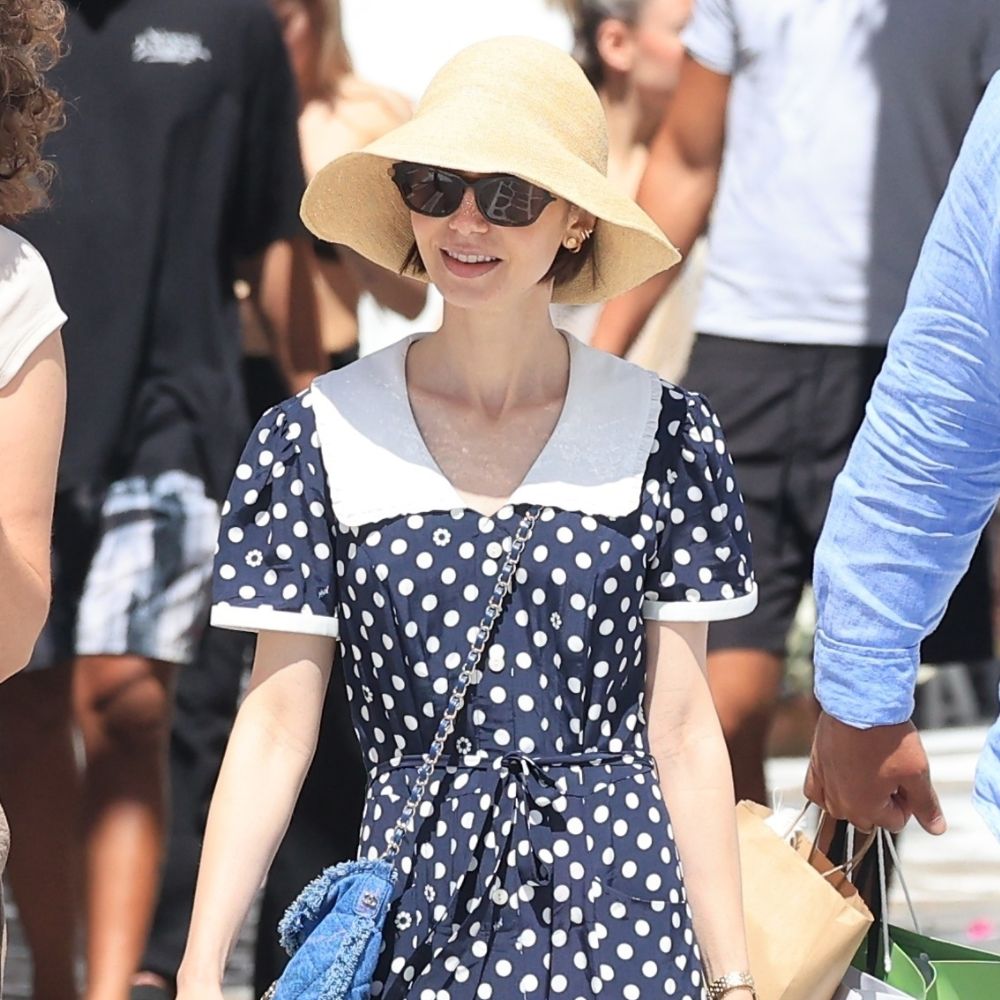 Lily Collins wears beige mesh ballet flats with a polka dot dress and a straw hat.