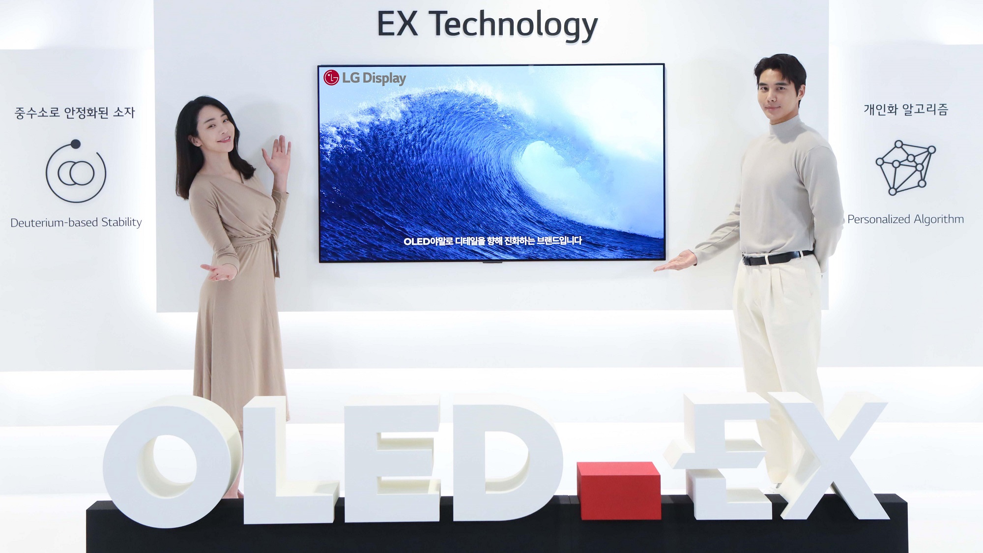 A man and a woman stand in front of an LG OLED EX television.