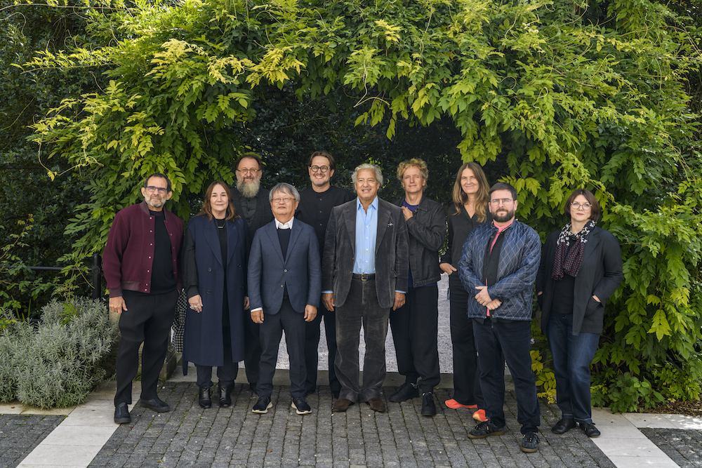 assembled group of designers standing in front of green foliage