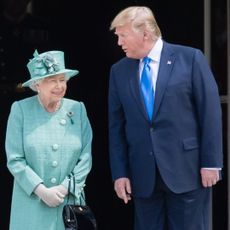 Queen Elizabeth in a turquoise coat next to Donald Trump wearing a blue suit