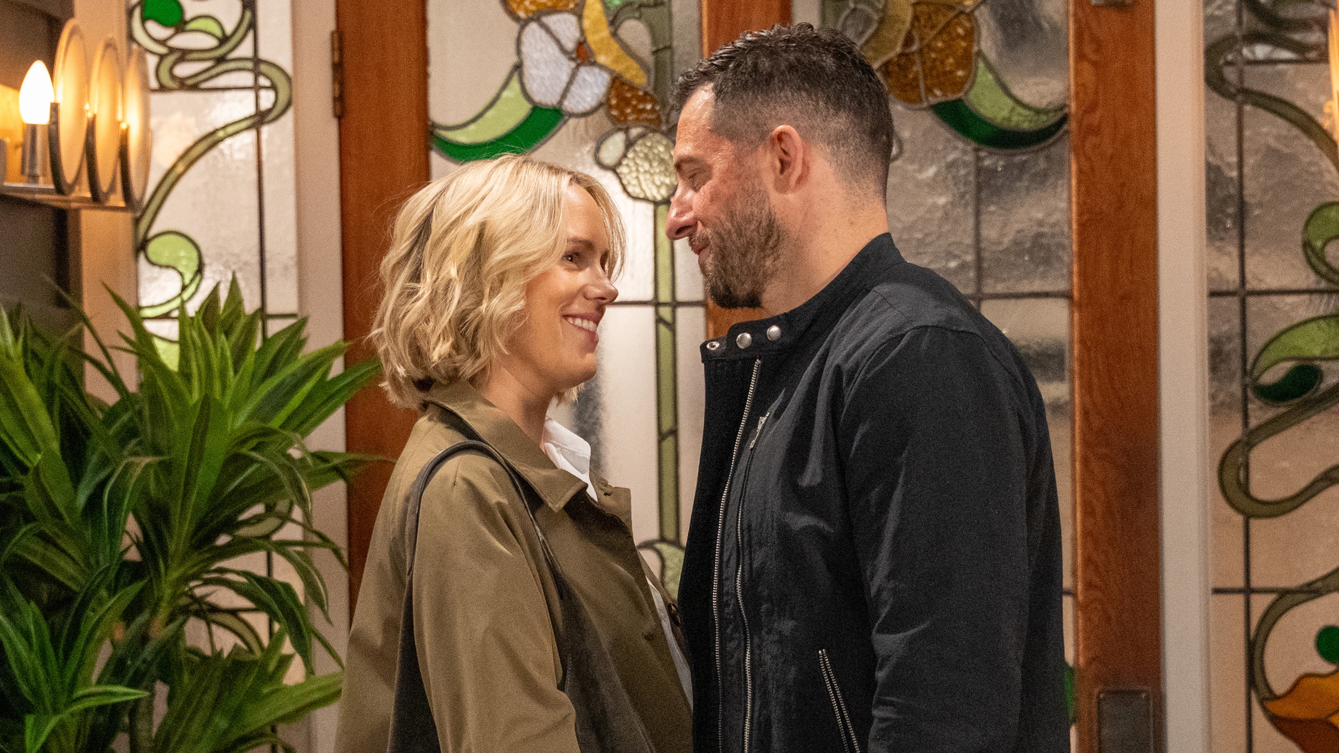 Steph and Ross smiling and looking into each other's eyes in front of a door