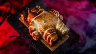 The Mini Stay-Puft S'more shown plated, on a black table, in front of a red curtain, for Universal Halloween Horror Nights 2024.