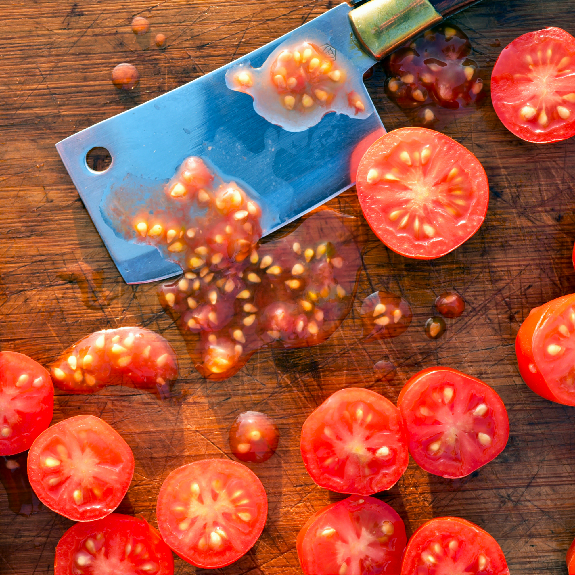 flat lay overhead view of kitchen still life scene close-up details of small grape tomatoes cut into halves with mini cleaver knife blade to extract seeds to save and sow next year