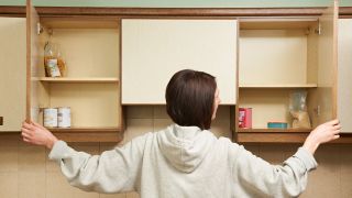 Woman looks in kitchen cupboards