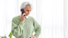 Frowning mature woman talking on telephone at home