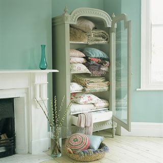 green wall with green armoire and cushions and throw