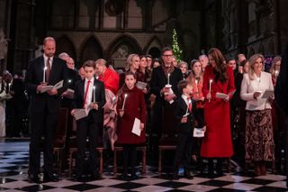 Prince William, Prince George, Princess Charlotte, Princess Kate, Duchess Sophie holding candles and standing up during a carol concert