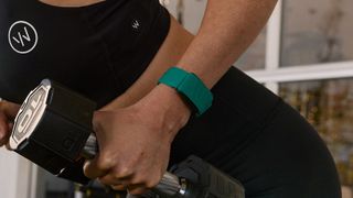 Woman lifting dumbbell while wearing Whoop device on wrist