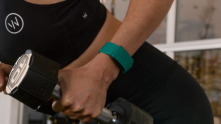Woman lifting dumbbell while wearing Whoop device on wrist