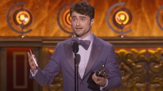 Daniel Radcliffe giving his Tony speech while holding a speech in his left and the Tony in his right.