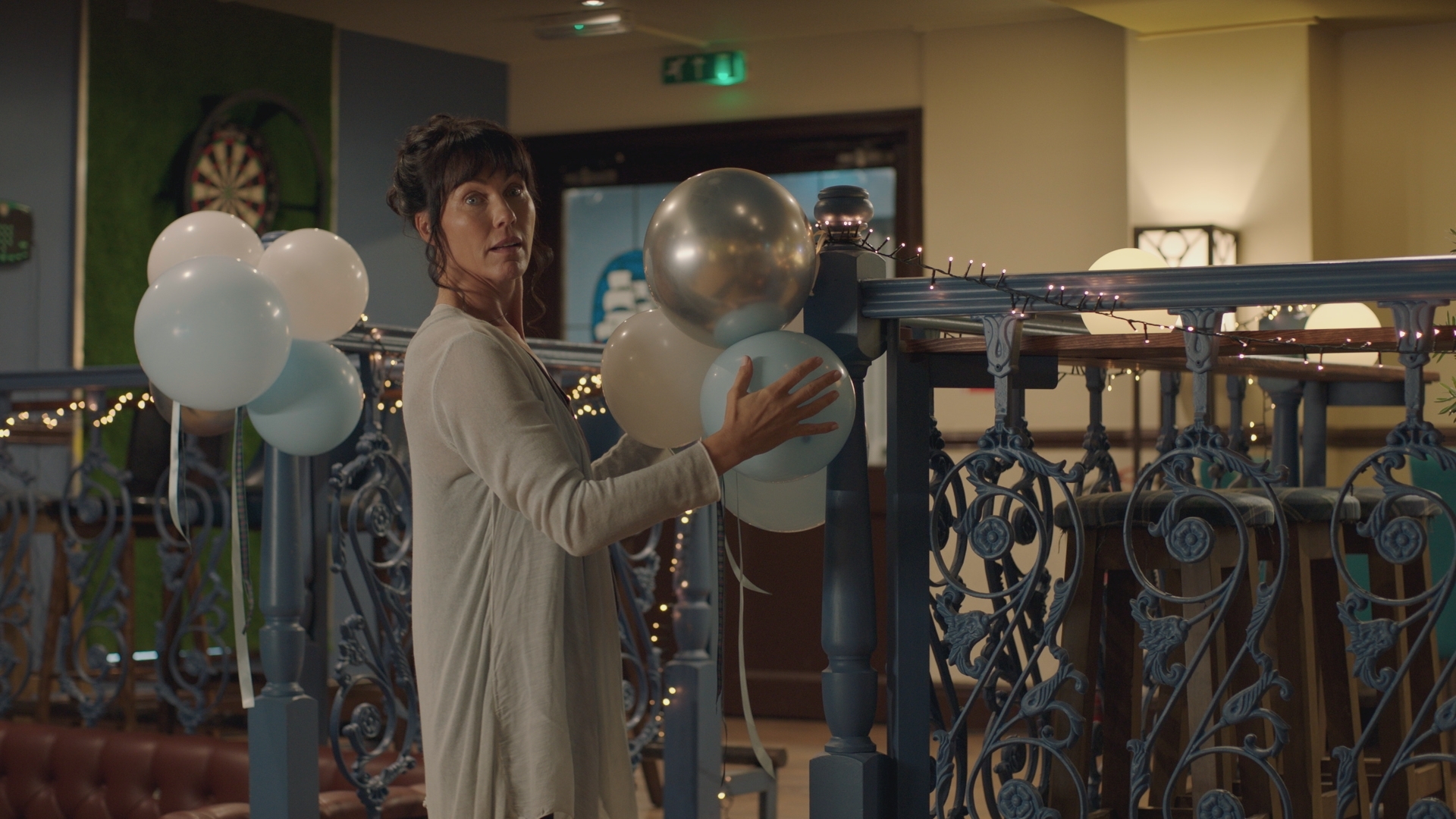 Faith Cadogan at the reception venue with her hair and make up done but wearing a long cardigan as she arranges balloons.