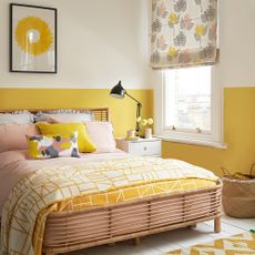 yellow bedroom with two tone wall floral blind black task lamp cane bed frame and yellow geometric rug