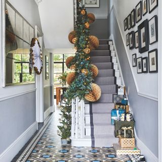 Grey hallway area with checkered tiles and garlands and decorations on the bannister