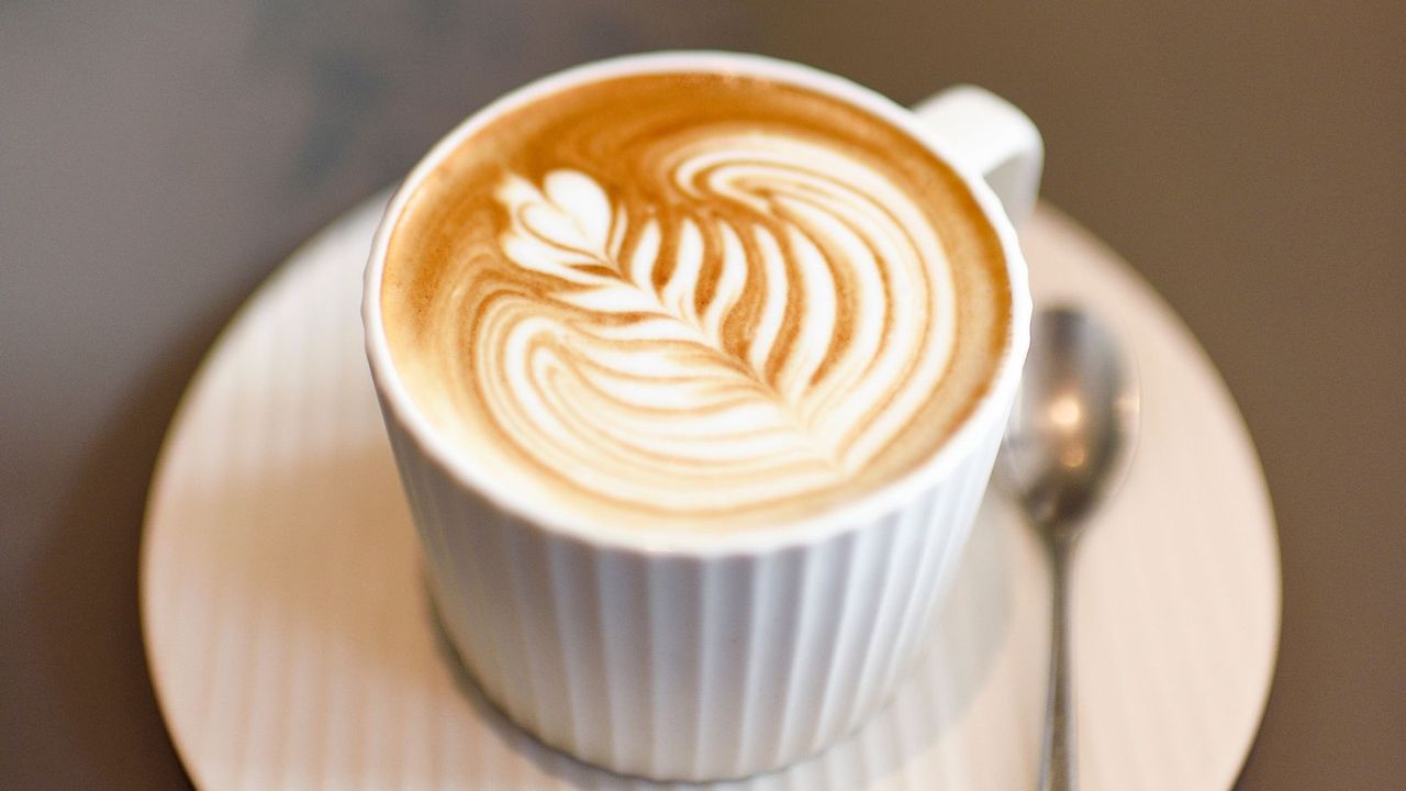 A latte in a white mug on a white saucer