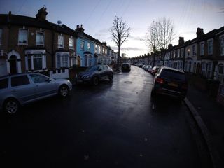 Street with water on and cars and houses taken in evening