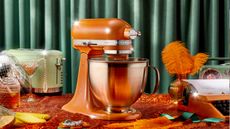 KitchenAid® Tangerine Twinkle Stand Mixer, surrounded by glamorous pearls, feathers, and disco balls
